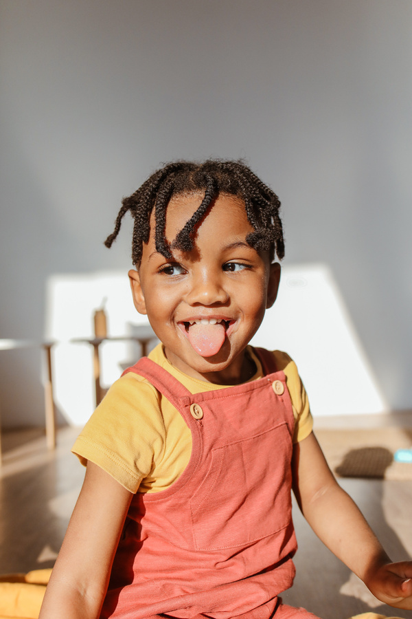 A toddler school aged child is smiling looking sideways  away from the camera 