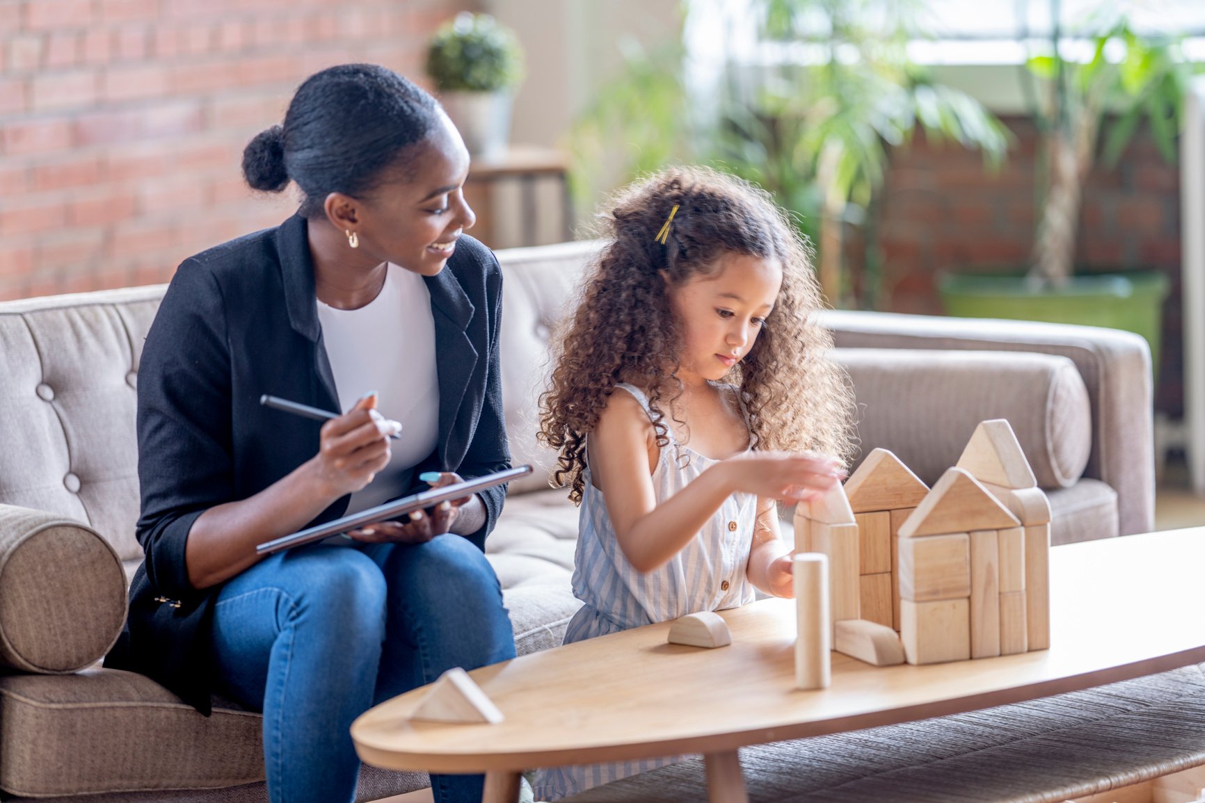 An educator or therapist  working together to with a build a play house of blocks