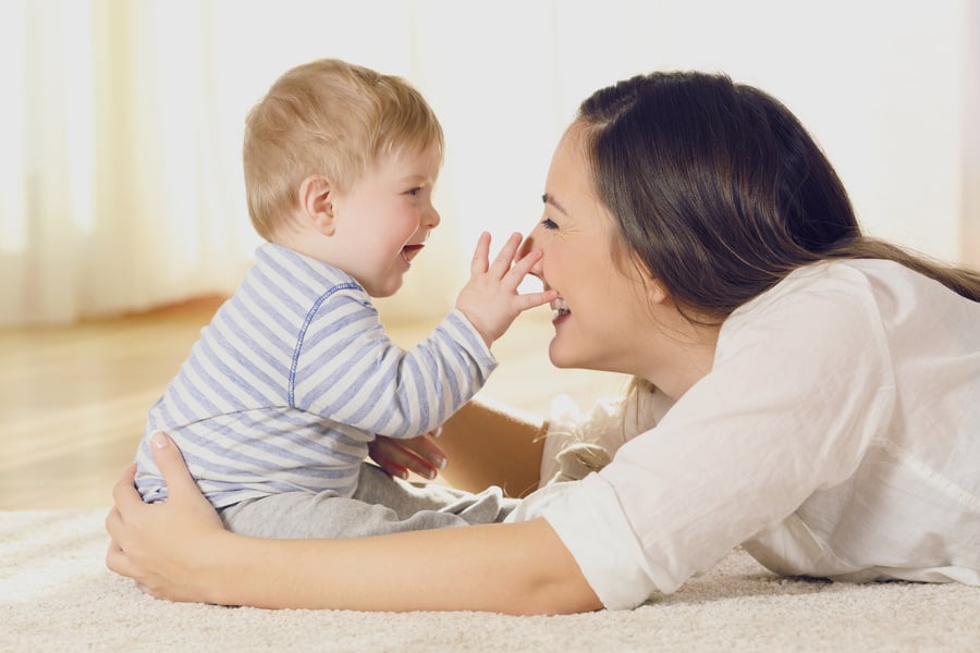 A mother and a baby are playing on the floor